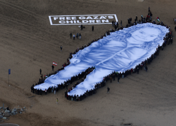 Retrato gigante de menina morta na guerra de Gaza é estendido em praia de Barcelona